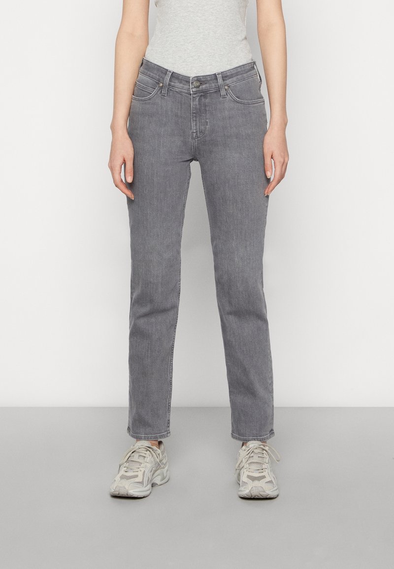 Grijze denim jeans met een recht gesneden ontwerp, vijf zakken, een knoopsluiting aan de voorkant en subtiele vervaging. Gemaakt in combinatie met lichtgekleurde sportschoenen.