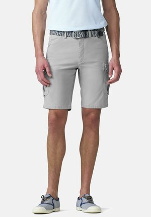 Mann trägt hellgraue Cargo-Shorts mit seitlichen Taschen, einen gewebten Gürtel, blaue Turnschuhe und ein weißes Hemd, steht vor weißem Hintergrund.