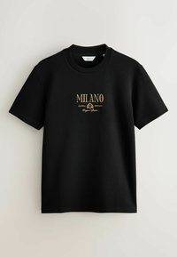 Camiseta de algodón negra con mangas cortas, que presenta texto bordado en oro "MILANO GLOBAL EDITION" y "Original Edition" en una fuente clásica.
