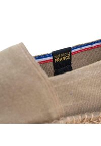 Chaussure en tissu beige avec une semelle en jute cousue. Présente une étiquette noire avec du texte doré indiquant "FABRIQUÉ À SOULE, FRANCE" et un accent rayé bleu-rouge-blanc.