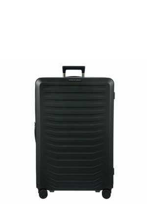 Valise rigide noire avec un design à rainures verticales, poignée rétractable, quatre roues et zip latéral. Construction durable et légère.