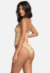 Enhelkelförande baddräkt med strapless-design. Har en ferskenfärgad bakgrund, blå cirkulära mönster och linjer. Tillverkad av stretchigt material.