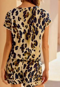 Kurzarm, locker geschnittenes Oberteil und Shorts-Set aus einem cremefarbenen Stoff mit einem auffälligen, mehrfarbigen Leopardenmuster. Strukturiertes Finish.