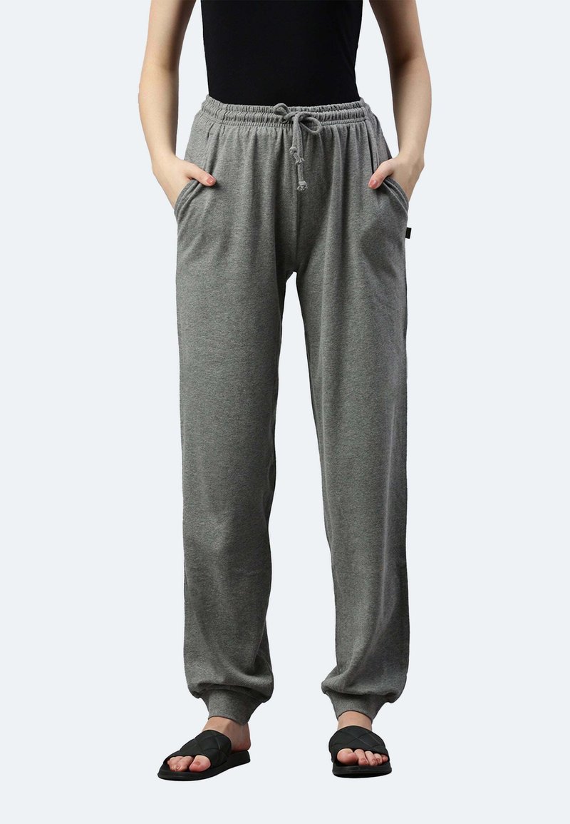 Graue, locker sitzende Sweatpants mit elastischem Bund und Kordelzug, ausgestattet mit Seitentaschen und schmal zulaufenden Beinabschlüssen. Kombiniert mit schwarzen Sandalen.