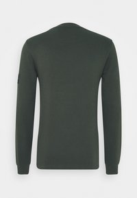 Mörkgrön långärmad tröja med rund halsringning, tillverkad av ribbat tyg. Har en liten svart logotyp på vänster ärm. Slät textur.