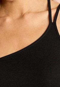 Black ribbed tank top featuring a one-shoulder design with thin straps. The fabric is textured, providing a fitted appearance.