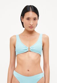 Világoskék, bordázott bikini felső, amely elöl csomó részlettel és kör alakú díszítéssel rendelkezik. A pántok szélesek és simák, szépen kiegészítve a dizájnt.