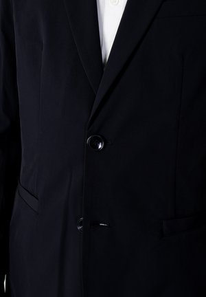 Blazer navy con tessuto testurizzato, chiusura a un bottone e due tasche frontali. Le alette affilate aggiungono al suo design su misura.