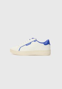 Hvite sneakers med blå detaljer, med en glatt lær overdel, perforert side og en teksturert såle. Merkevaren logo synlig på siden.