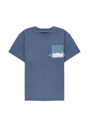 T-shirt blu a manica corta con una piccola tasca frontale disegnata come una faccia di squalo sorridente con occhi e denti sul petto.