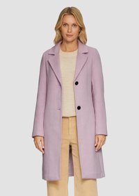 Lichtpaarse wollen jas met notch-revers, twee zwarte knopen en zijzakken, gedragen over een beige trui en lichtbeige broek.