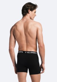 Schwarze Boxershorts mit breitem Bund, auf dem "A ALLSAINTS" in Weiß steht. Der Stoff wirkt glatt und eng anliegend, ausgelegt für maximalen Komfort.