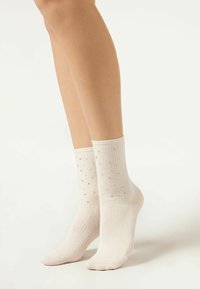 Stopki w kolorze off-white, z prążkowaną teksturą i rozsianymi złotymi akcentami dla dodatkowego uroku. Elastyczny materiał zapewniający komfort noszenia.
