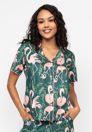 Korte mouwen pyjama top met een groene achtergrond, een patroon van roze flamingo's en bladeren. Heeft een knoopsluiting aan de voorkant en een kraag.