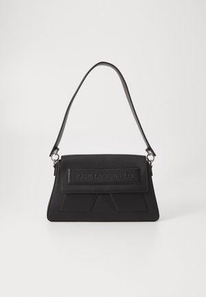 Black handbag featuring a textured surface, a fold-over flap with embossed logo, and a slim shoulder strap. Rectangular shape with angular accents.