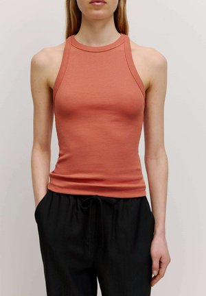 Rostfarbener gerippter Tanktop mit hohem Ausschnitt und taillierter Passform. Kombiniert mit lockeren schwarzen Hosen mit einem verstellbaren Bund.