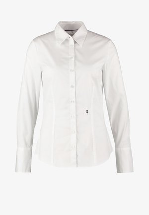 White long-sleeve shirt featuring a pointed collar, button front, and curved seams. Includes a small black flower logo on the left side.