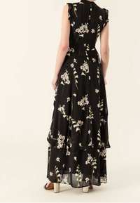 Černé květinové maxi šaty s vrstveným designem, volány a volným střihem. Obsahují světle barevné květinové vzory po celém povrchu.