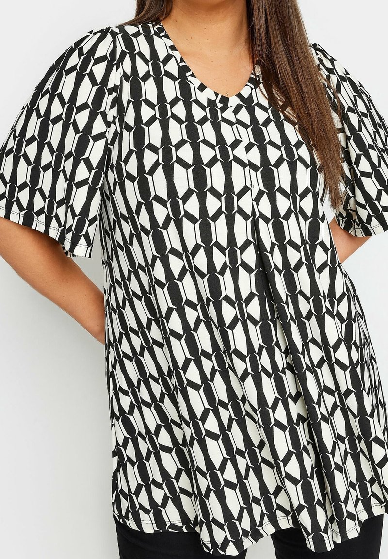Blouse imprimée en noir et blanc avec un motif géométrique, manches courtes et décolleté en V, réalisée dans un tissu léger.