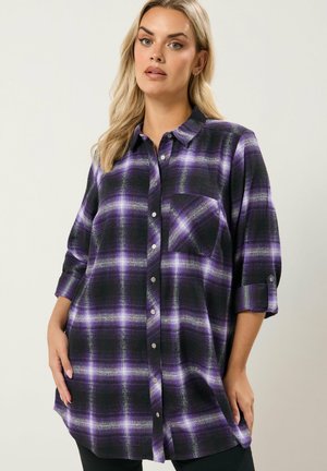 Camicia di flanella a maniche lunghe nera con motivo a quadri viola. Caratterizzata da una chiusura con bottoni sul davanti e una tasca singola sul petto. Texture morbida.