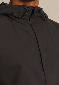 Czarna wodoodporna kurtka z wysokim kołnierzem, regulowanym kapturkiem na sznurek i pełnym zamkiem z przodu. Gładka tekstura i minimalistyczny design.