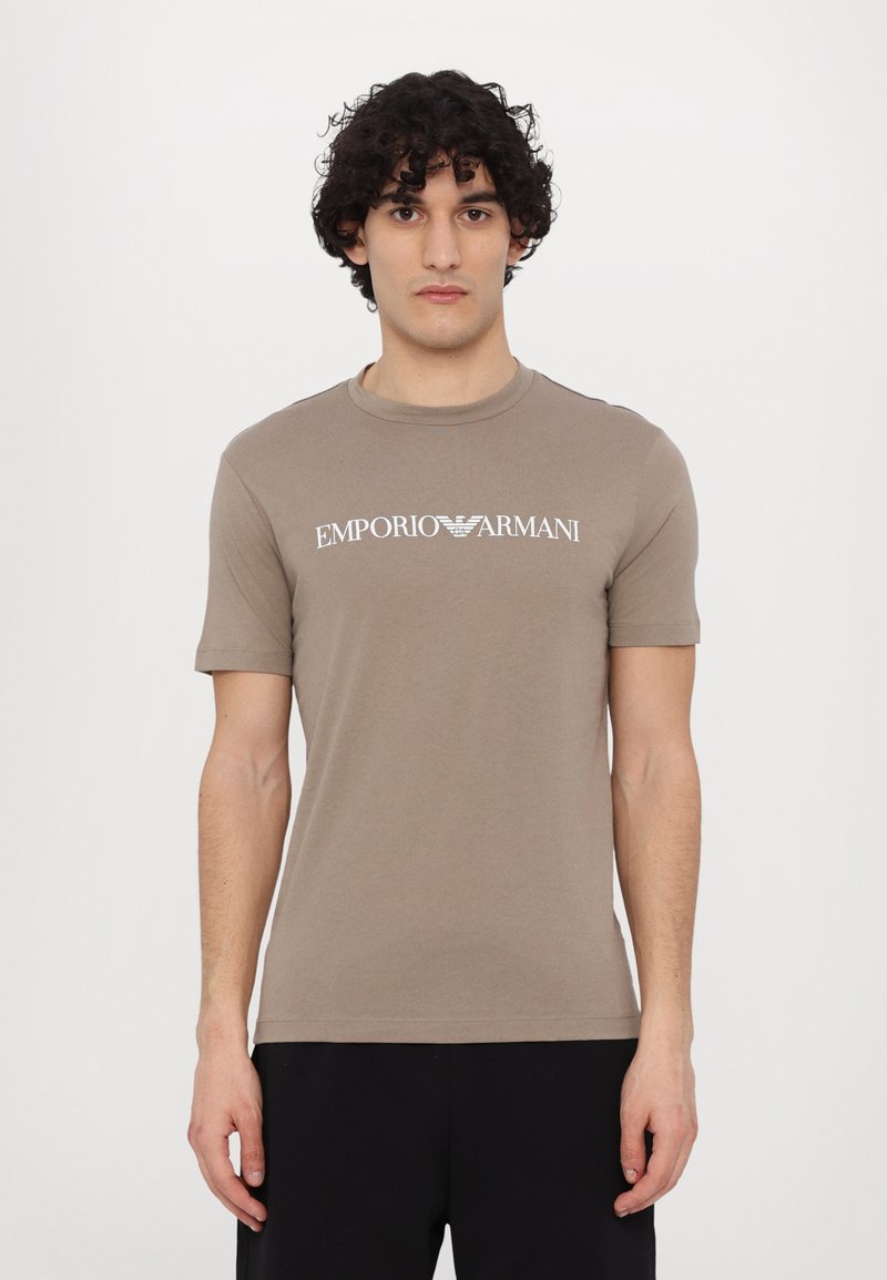 Brown short-sleeve t-shirt made of cotton, featuring a white "Emporio Armani" logo across the chest. Simple round neckline and fitted design.
