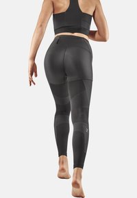 Black athletic leggings with a textured panel design and a fitted silhouette. Includes a rear zip pocket and a matching crop top.