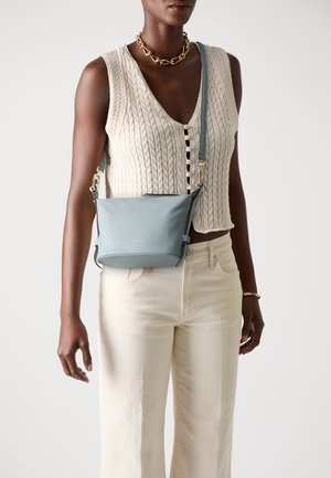 Sac bandoulière en cuir bleu clair avec un léger brillant, de forme rectangulaire, matériel doré et une sangle réglable. Texture lisse.