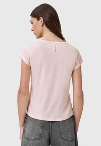 Maglietta corta a maniche corte di colore rosa chiaro con vestibilità rilassata, scollatura tonda e piccolo dettaglio dell'etichetta sul retro. Tessuto in cotone morbido e strutturato.