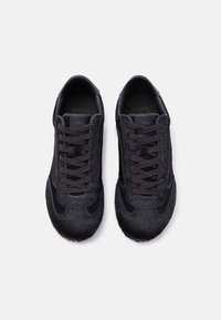 Ζευγάρι μαύρα χαμηλά αθλητικά παπούτσια με υφή σουέτ και σχέδιο με κορδόνια, απεικονιζόμενα από πάνω σε λευκό φόντο.