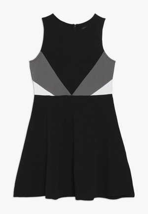 Robe noire avec une jupe évasée, présentant des panneaux bicolores gris et blanc sur le corsage. Confectionnée en tissu extensible, design sans manches.