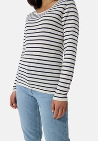Maglione a maniche lunghe con collo a girocollo, caratterizzato da righe orizzontali blu navy e bianche. Tessuto morbido con vestibilità dritta. Abbinato a jeans di denim blu chiaro.