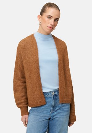 Bruine gebreide cardigan met een open voorkant, lange mouwen en een zachte textuur, gedragen over een lichtblauwe coltrui. Denim jeans maken de look compleet.