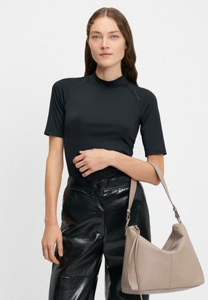 Czarny top z krótkim rękawem i wysokim dekoltem, w połączeniu z czarnymi, błyszczącymi skórzanymi spodniami. Trzymana jest jasnoszara torebka o zaokrąglonym kształcie.