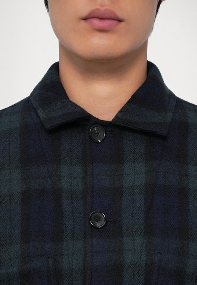 Giacca camicia in lana a quadri nei toni del blu e del verde, con chiusura a bottoni neri, colletto classico e tessuto strutturato.