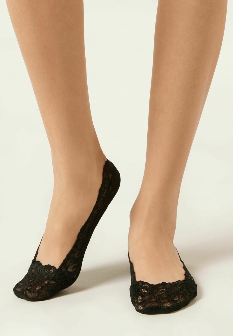 Schwarze Spitzensocken ohne sichtbaren Bund mit gewelltem oberen Rand und passgenauer Form, entworfen, um nur den Fuß zu bedecken, ohne sichtbare Linien.