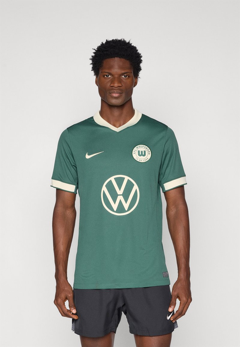 Roheline Nike jakk kreemjate aktsentidega ja Volkswageni logo, millel on V-kaelus ja lühikesed varrukad. Materjal tundub hingav.