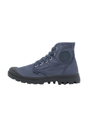 Hoher marineblauer Canvas-Stiefel mit schwarzer Gummisohle und Zehenkappe, Schnürung vorne und rundem Logo-Patch am Knöchel.