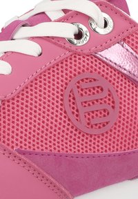 Rosa Sportschuh aus Netzmaterial mit glatten synthetischen Akzenten, weißen Schnürsenkeln und einem runden Logo an der Seite.
