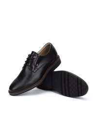 Chaussures habillées noires en cuir avec une finition lisse, bout arrondi, design à lacets, et semelle en caoutchouc texturée présentant un motif subtil.