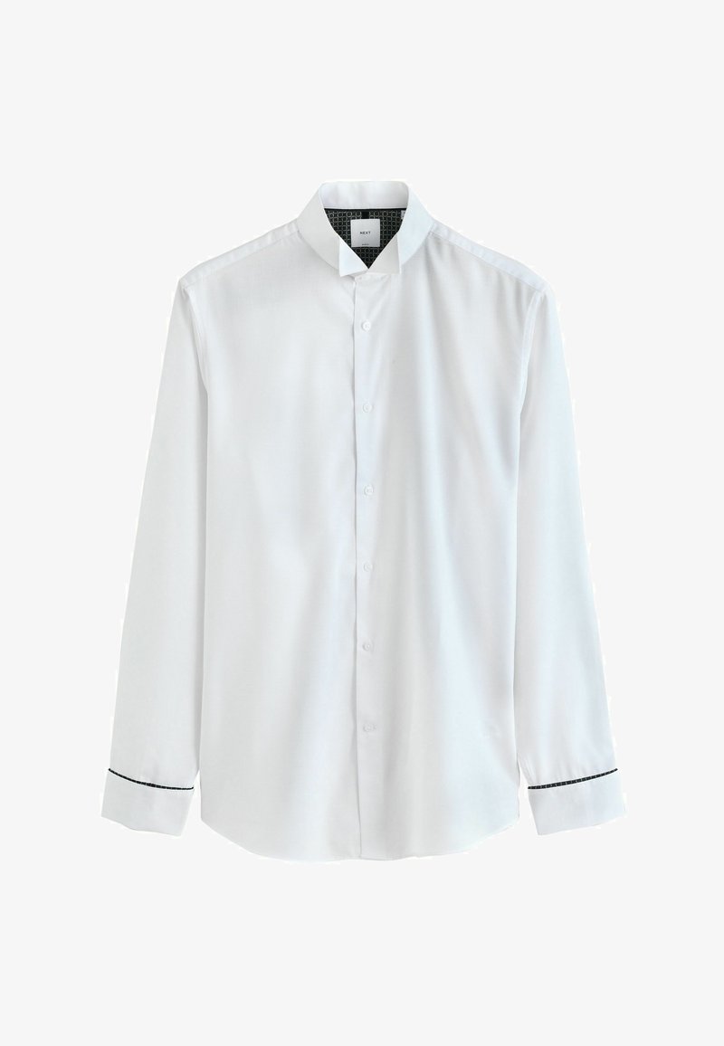 Camisa blanca de manga larga con cuello mandarín y ribetes negros en los puños, exhibida sobre un fondo blanco.