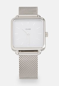Vierkante zilveren horloge met een witte wijzerplaat, minimalistische uurmarkeringen en een stalen mesh armband. Bevat een kleine kroon aan de zijkant.