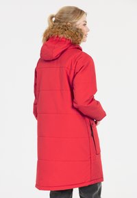 Rød isoleret parka med en hætte foret med pels, lange ærmer og lige snit. Indeholder sidelommer og en glat stofstruktur.