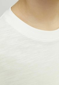 White cotton T-shirt with a textured, slightly shiny surface and a crew neckline, showing soft fabric without visible patterns or accents.