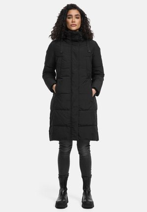 Zwarte gewatteerde jas met een hoge kraag, voorzien van een ritssluiting, voorzakken en een lengte tot de knie. Draagt met donkergrijze broek en laarzen.