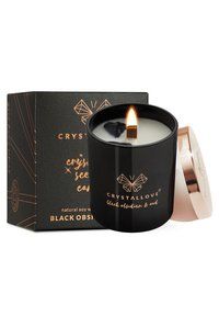 Candela nera in un barattolo di vetro nero opaco con coperchio dorato, dotata di stoppino in legno e cristalli di ossidiana nera. Accompagnata da una confezione decorativa.