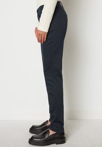 Pantaloni blu navy realizzati in tessuto elasticizzato, design affusolato, stile a cinque tasche, con vita media e dettagli di cucitura sottili.