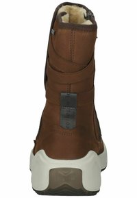 Hnědá kožená bota s chlupatým podšívkou a elastickými detaily. Výrazná vyvýšená podrážka a zip na boku pro snadné obouvání.