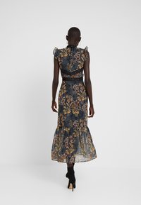 Maxikleid aus transparentem, dunklem Stoff mit floralem Druck; Rüschenträger, taillierter Schnitt und ausgestellter Saum. Schwarze Spitzenakzente verleihen dem Design das gewisse Etwas.