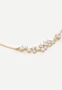 Goldkette mit runden, klaren Edelsteinen, die in einer geschwungenen Linie angeordnet sind, mit unterschiedlichen Größen und einer zarten Kette.